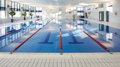 Bild på Rosengårdsbadets inomhusbassäng, med kritvita väggar och fönster som släpper in ljus från vänster.