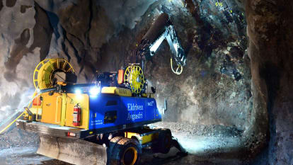 En borrmaskin hackar längs bergsväggen under bygget av en tunnel