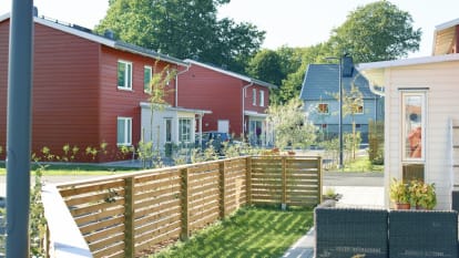 Utsikt över en liten småhusgata med nyplanterade träd och hus i olika färger.