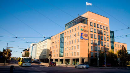 Three buildings in classic modernist style, in facade colours of red, pale yellow, and blue, respectively.