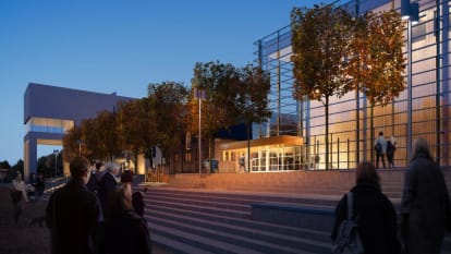 The entrance to the Royal College of Music in Stockholm. It is during a dark, winter evening with the massive glass walls encompassing the entrance.