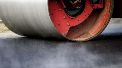 Close up of a road roller evening out freshly paved asphalt.