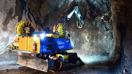 En borrmaskin hackar längs bergsväggen under bygget av en tunnel