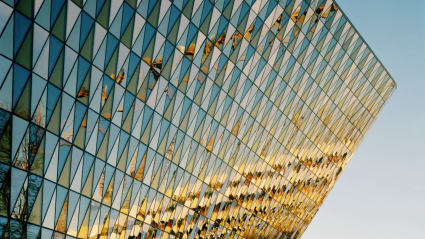 Detaljbild på Nya Aulan, Karolinska institutet. Triangulära glasformer mönstrar väggen. En annan byggnad reflekterar sig på väggen.