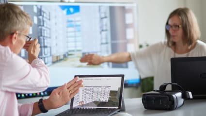 Two workers look at and discuss a 3D sketch.