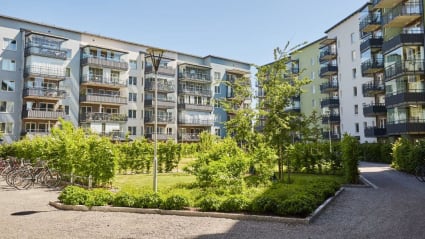 Image of white apartment houses and a neighborhood garden.