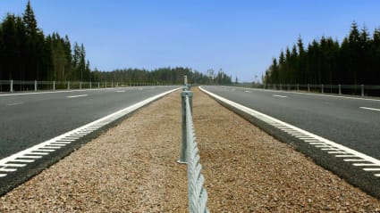 View of a motorway running off into the distance with Nordic landscape around it.