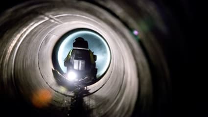 Bild på en vattenlednings tunnel, med en maskinist synlig i slutet av rörtunneln.