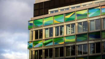 Närbild på en fasad som till största delen består av fönster, både färgade och ofärgade.