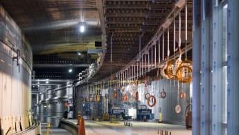A station inside Malmös Citytunneln under construction. Cords for the station lights are hanging from the roof, and machines are working in the background.