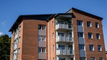 Bild på ett hus med röd tegelfasad och balkonger som ligger "insprängda" i fasaden.