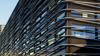 Closeup of the office building, with the black outer structure and windows enclosed within a special kind of "cage" exterior.