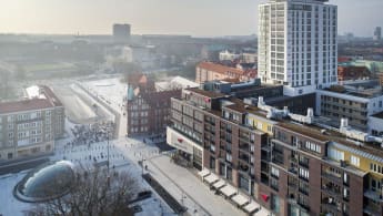 Aerial view over the new Triangeln shopping centre in light snow cover. Several buildings of varying size and colour, along with the plaza and entrance to the underground railway station.