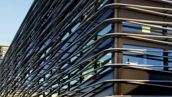 Closeup of the office building, with the black outer structure and windows enclosed within a special kind of "cage" exterior.