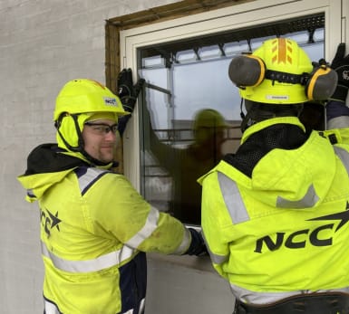 En arbetare sågar genom trä.