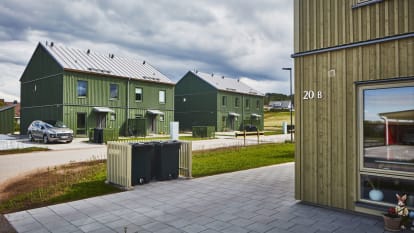 Drönarbild av bostadsområde med flera gröna och gula hus.