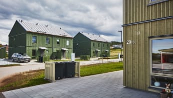 Drönarbild av bostadsområde med flera gröna och gula hus.