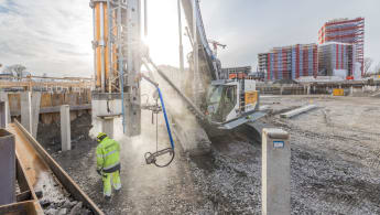 Workers operating a piling machine on a construction site.