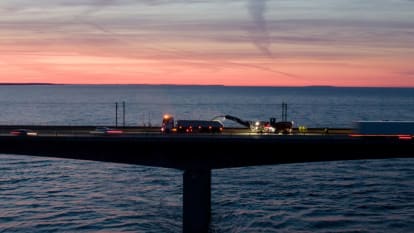 Bild på Öresundsbron, en lastbil som kör över bron samt vatten och solnedgång i bakgrunden.
