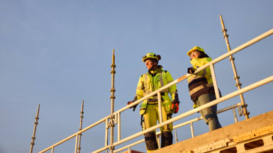A group of people look at drawings on a table.