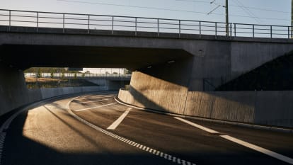 Arbetare i varselkläder står under en bro.