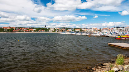 Bild tagen från sjö i Hudiksvalls kommun som visar en strand, hus och båtar.