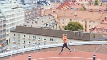 A woman runs at a rooftop running track.