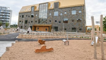 Illustration av en idrottshall omvigen av träd och gångväg.