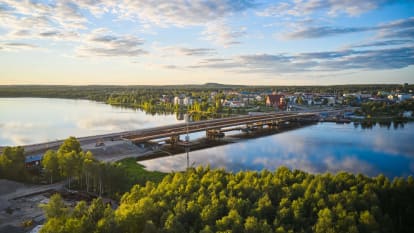 Bild på Kalixbron som går över en älv omgiven av skog.