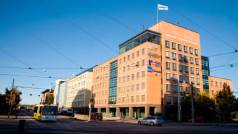 Three buildings in classic modernist style, in facade colours of red, pale yellow, and blue, respectively.