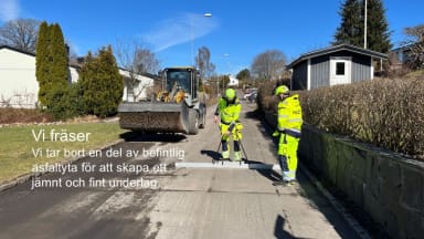 Bilden visar ett bostadsområde i vårsol. En borstmaskin står på vänster sida av gatan. Till höger ser vi en person i varselkläder som mäter om ytan är vågrät med ett stort vattenpass. Ytterligare en person i varsel tittar på. Texten i bilden lyder: Vi fräser. Vi tar bort en del av befintlig asfaltyta för att skapa ett jämnt och fint underlag.