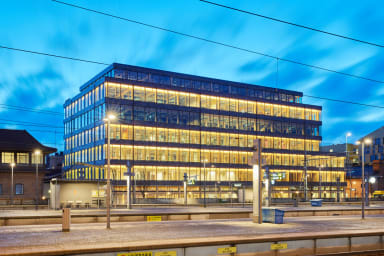 Two workers looks out from the ongoing construction of Våghuset, Gothenburg, with its wavy wall panels.