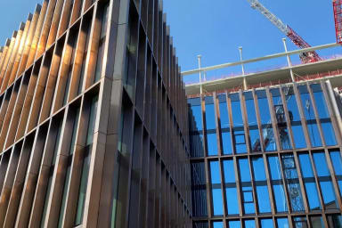 A cyclist moving along a street with newly built houses surrounding it.