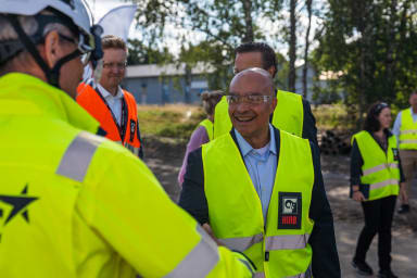 Peruskivenmuuraustilaisuuteen 19.8.2026 tervehdyksensä toivat myös Hiab-konsernin toimitusjohtaja Scott Phillips (kuvassa keskellä) johtoryhmineen sekä Hiab Raision tuotantojohtaja Jussi Peltoniemi (oranssissa liivissä).