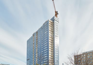 Two workers looks out from the ongoing construction of Våghuset, Gothenburg, with its wavy wall panels.