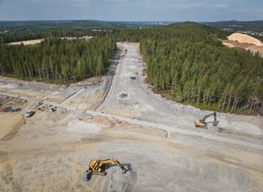 Drönarbild över Bergsbyns företagspark. Man ser ett stort område med byggvägar, skog och två grävmaskiner.