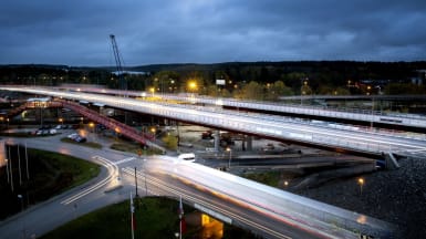 The new Rotebro bridge at night, with cars speeding by and nature visible in the background.