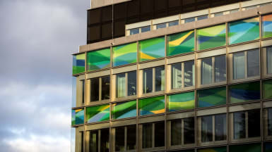 Närbild på en fasad som till största delen består av fönster, både färgade och ofärgade.