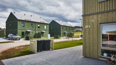 Drönarbild av bostadsområde med flera gröna och gula hus.