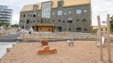 Illustration av en idrottshall omvigen av träd och gångväg.