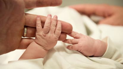 En bebis håller om en vuxen hand.