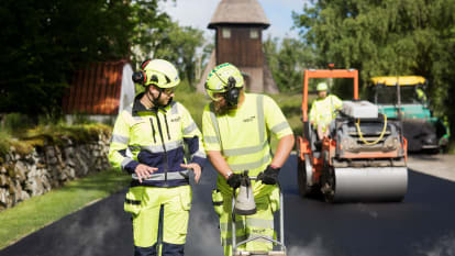 Bild på två arbetare samt ångvält i bakgrunden.