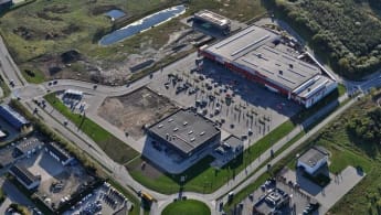 Aerial view of Herredscentret, with a large parking space and store buldings.