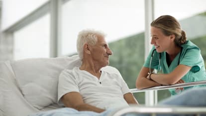Picture of an elderly man socializing with a hospital worker.