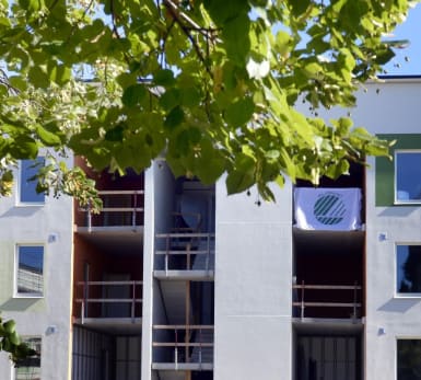 Bild på ett lägenhetshus där en textil med Svanenmärket fladdrar längs med en balkong.