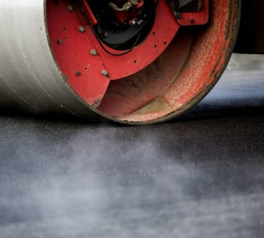 Close up of a road roller evening out freshly paved asphalt.