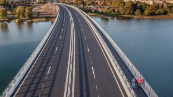 Bild på Kalixbron som går över en älv omgiven av skog.