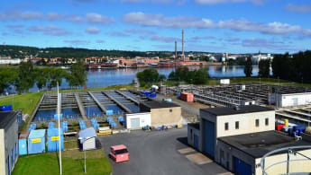 Simsholmens avloppsreningsverk. Stora utomhusbassänger och små fordonsgarage, med Jönköping över sjön i bakgrunden.