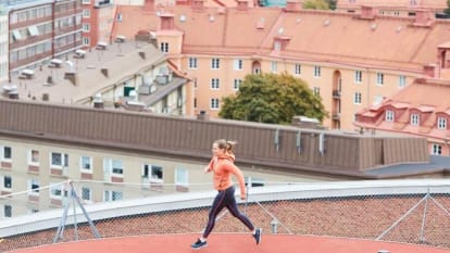 A woman runs at a rooftop running track.