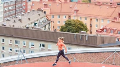 A woman runs at a rooftop running track.